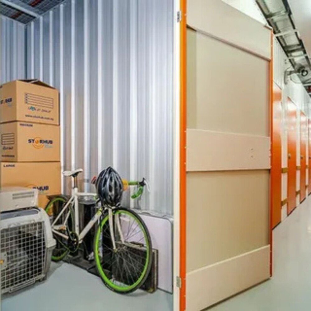 Storage unit containing packed boxes, a bicycle, and pet carrier, neatly organized inside. Ideal for temporary personal or household storage.