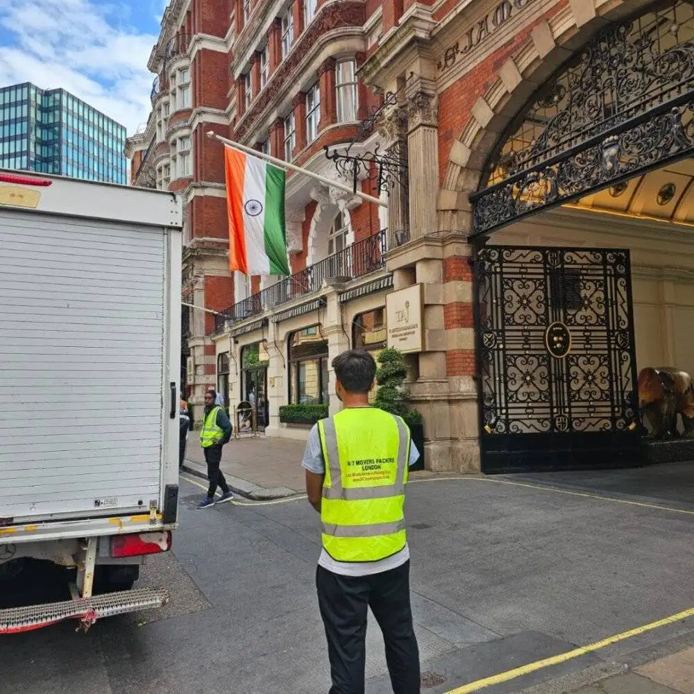 Team from 24/7 Movers Packers London outside Taj Hotel London near Indian flag, ready to perform premium relocation services with moving truck parked by the entrance.