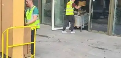 Two team members of 24/7 Movers Packers London one is standing with a trolley full of packed boxes and other is carrying trolley into the house/flat/room