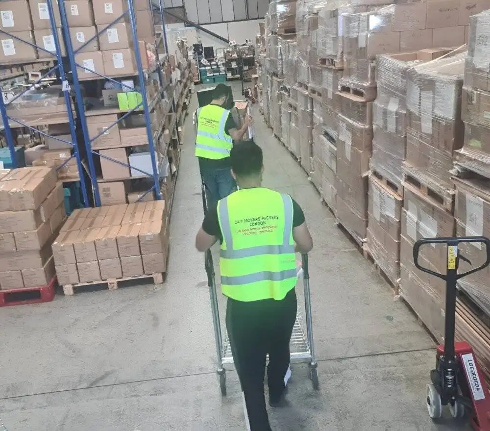 two workers are in the storage section and holding trolleys and there are packed stuff in these trolleys